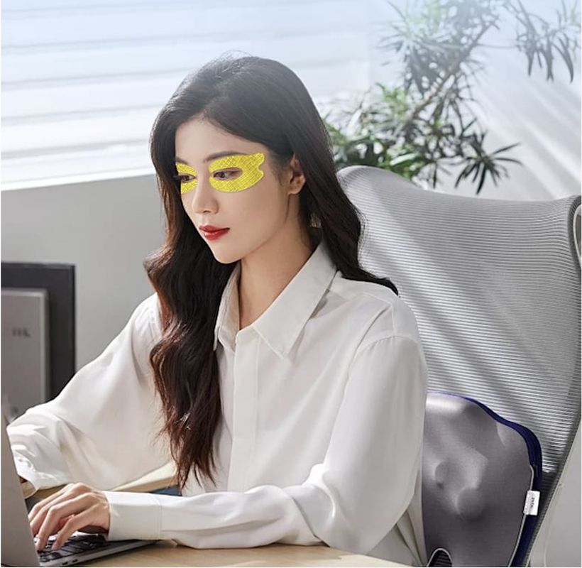 Woman wearing Eye Sabai cooling gel eye patches while working at her desk